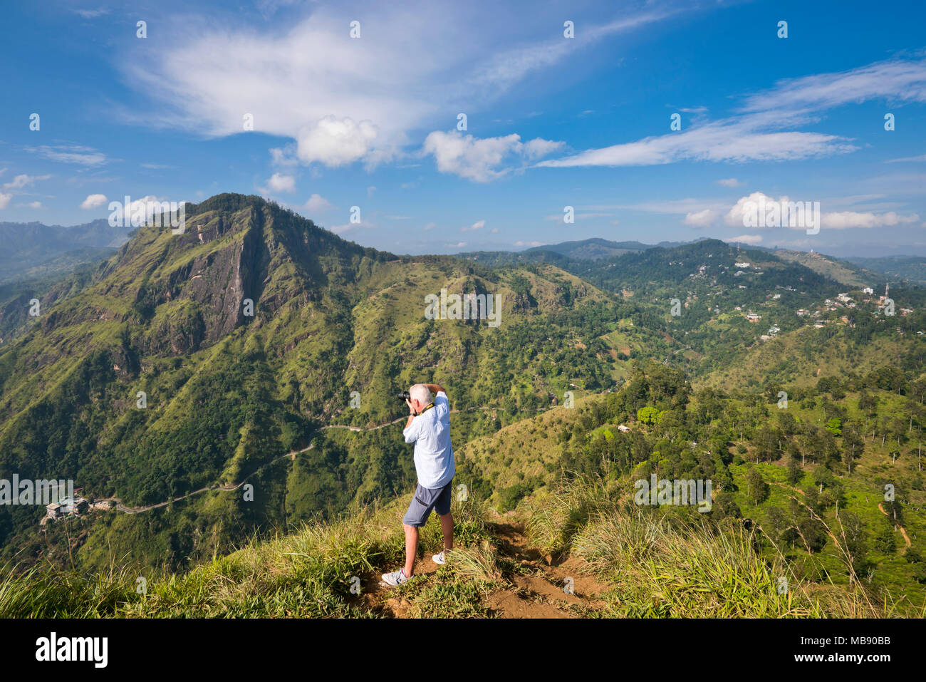 Horizontal portrait of a tourist taking photos of Ella Rock from Little Adam's Peak in Ella, Sri Lanka. Stock Photo