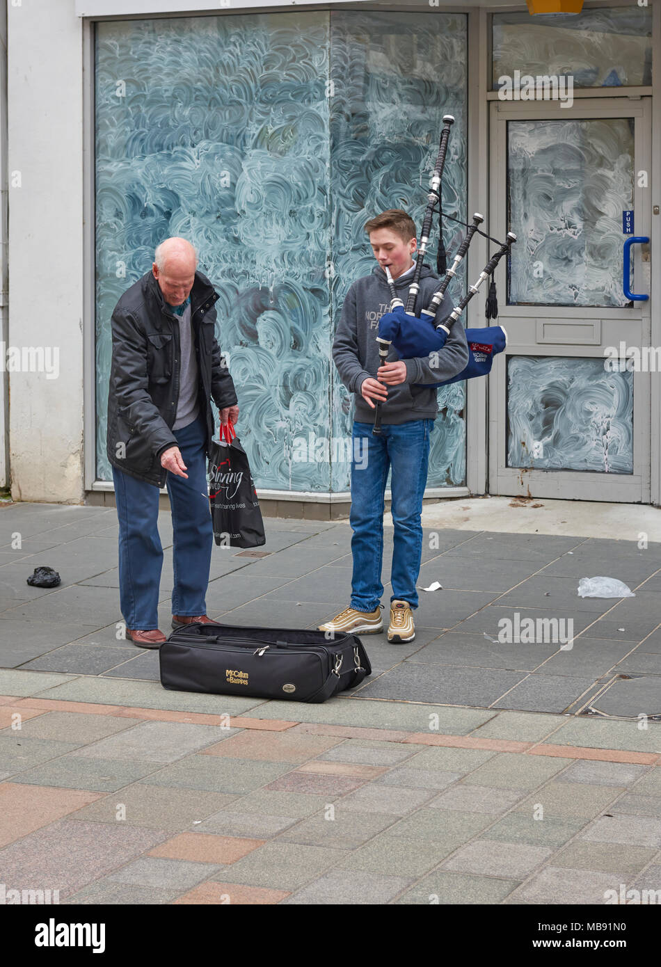 A Young Busker playing the bagpipes to an appreciative audience in the High Street of Perth one Saturday afternoon in April. Stock Photo