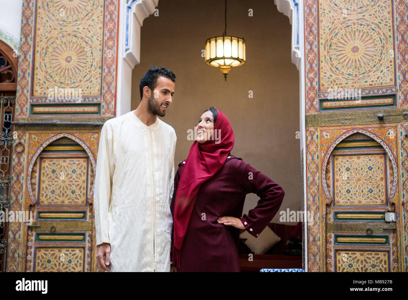 Young Muslim couple in relationship talking and smiling in traditional Moroccan riad house Stock Photo