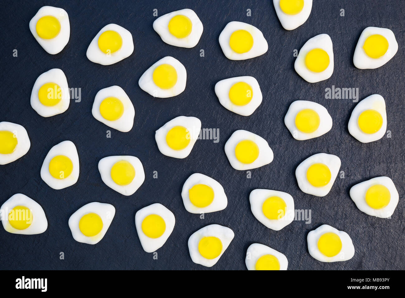 Fried eggs candy sweets overhead on dark background Stock Photo
