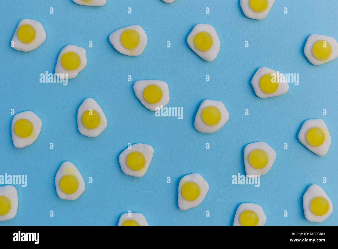 Fried eggs candy sweets overhead on bright blue background Stock Photo