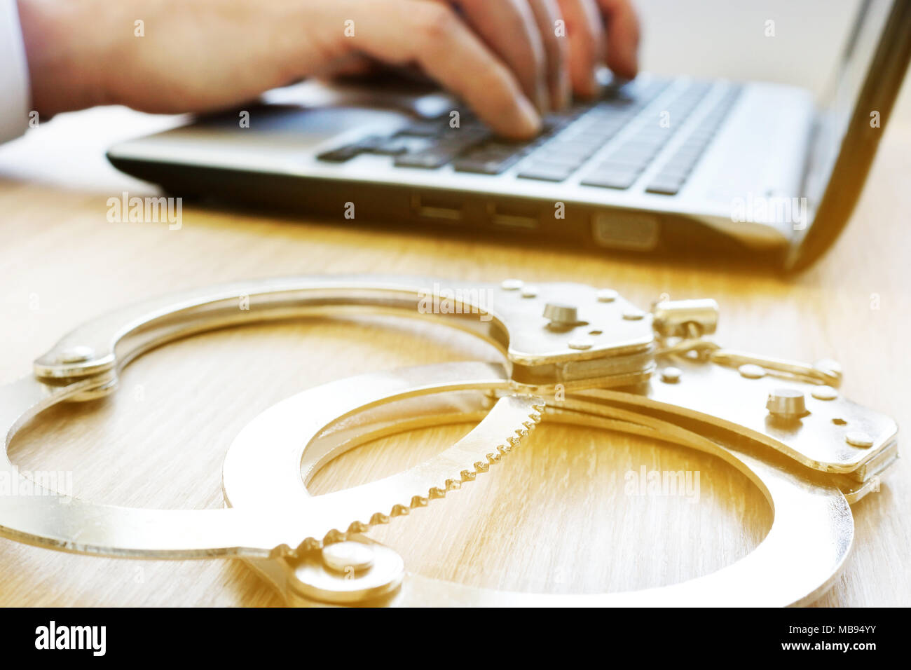 Computer crime. Man with laptop and handcuffs. Investigation concept. Stock Photo
