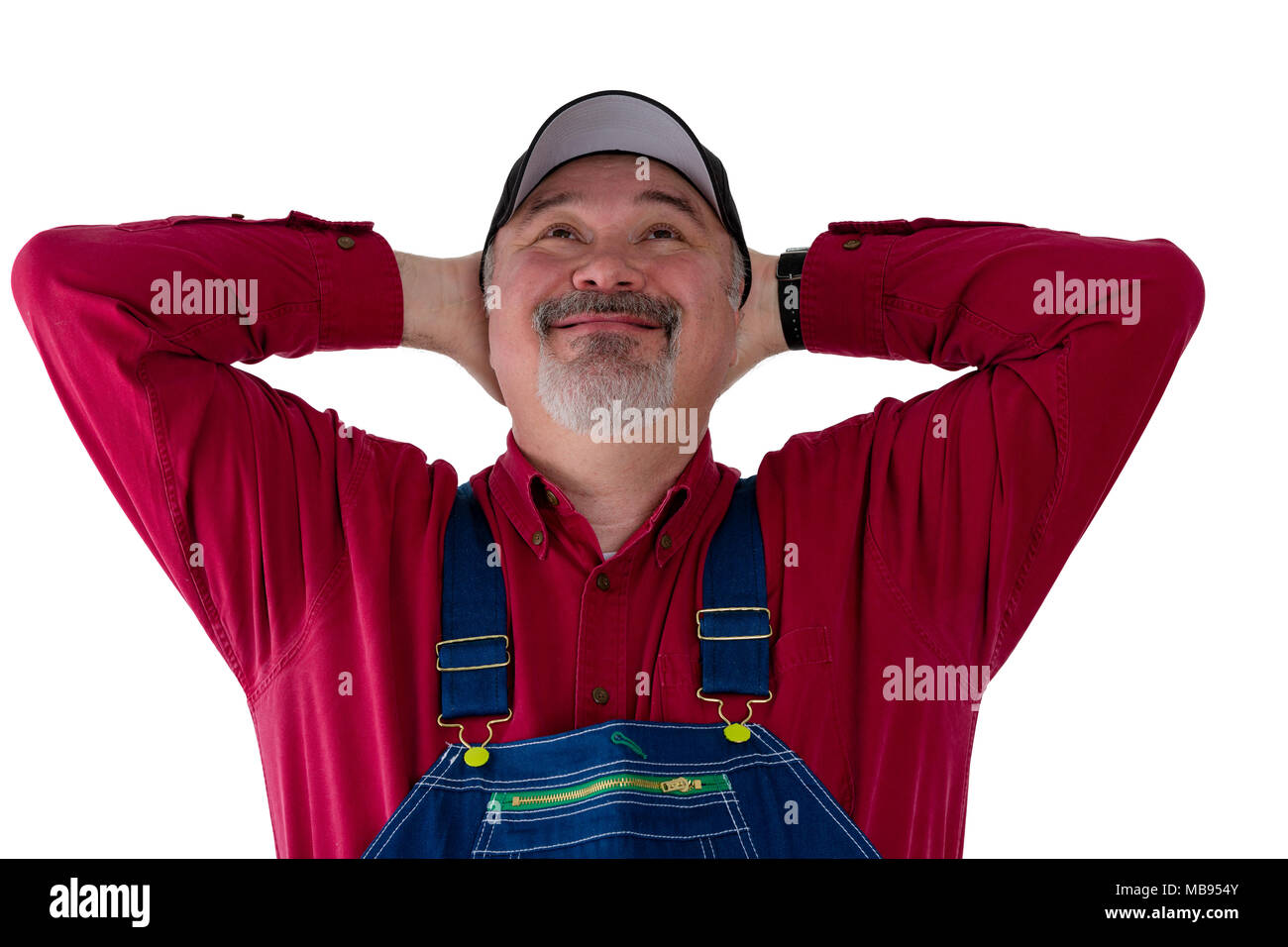 Pleased farmer or worker in dungarees looking up beaming in satisfaction at his success or good fortune isolated on white Stock Photo