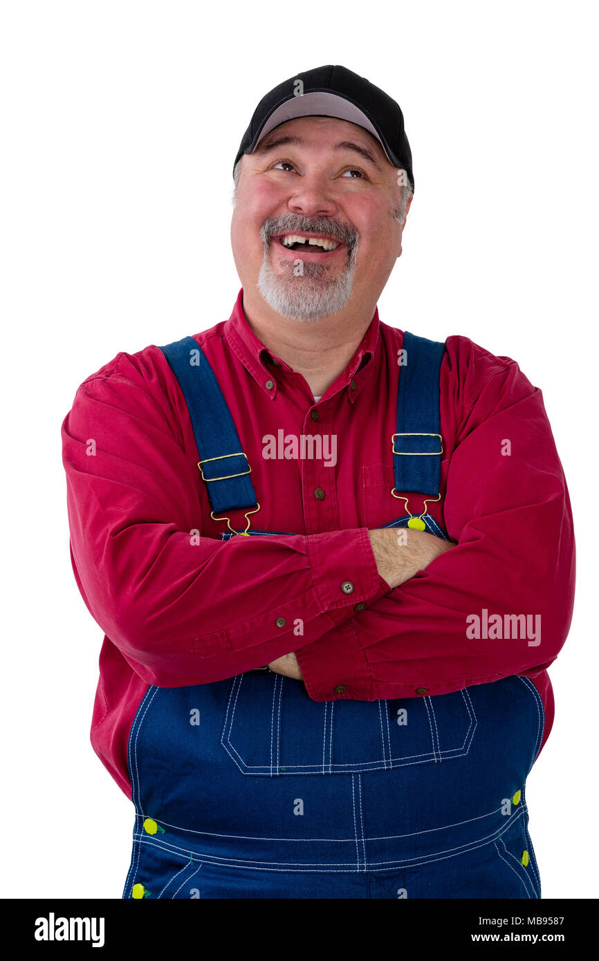 Pleased successful farmer in bib overalls or dungarees standing with folded arms looking up with a happy smile isolated on white Stock Photo