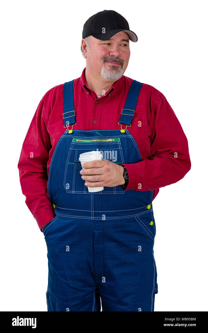 Thoughtful farmer or worker looking to the side with a quiet smile while standing holding a cup of takeaway coffee isolated on white Stock Photo
