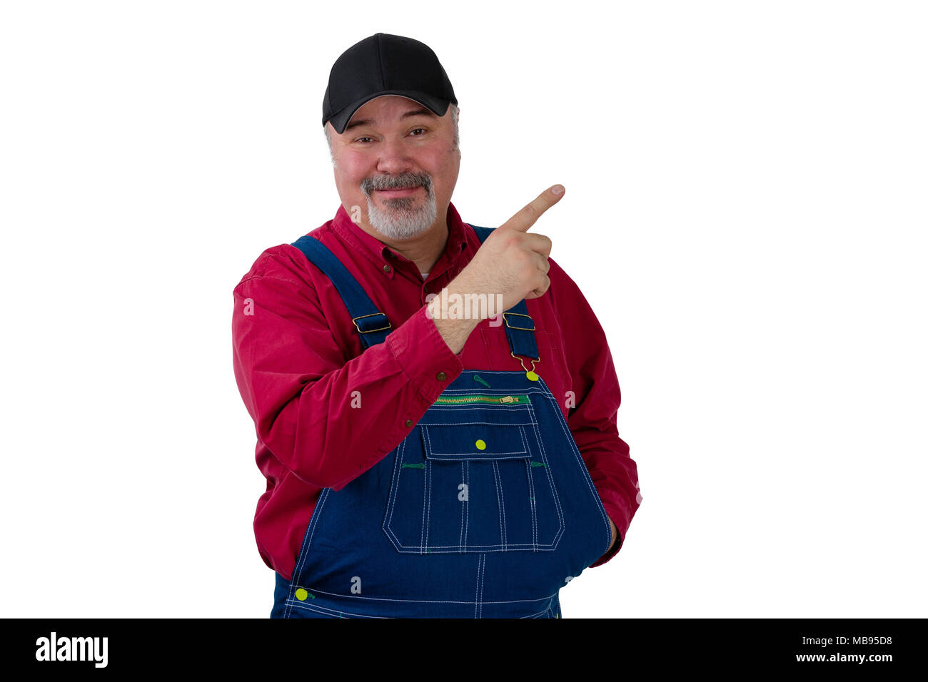 Happy farmer or worker in denim dungarees pointing upwards with a pleased smile towards blank copy space isolated on white Stock Photo