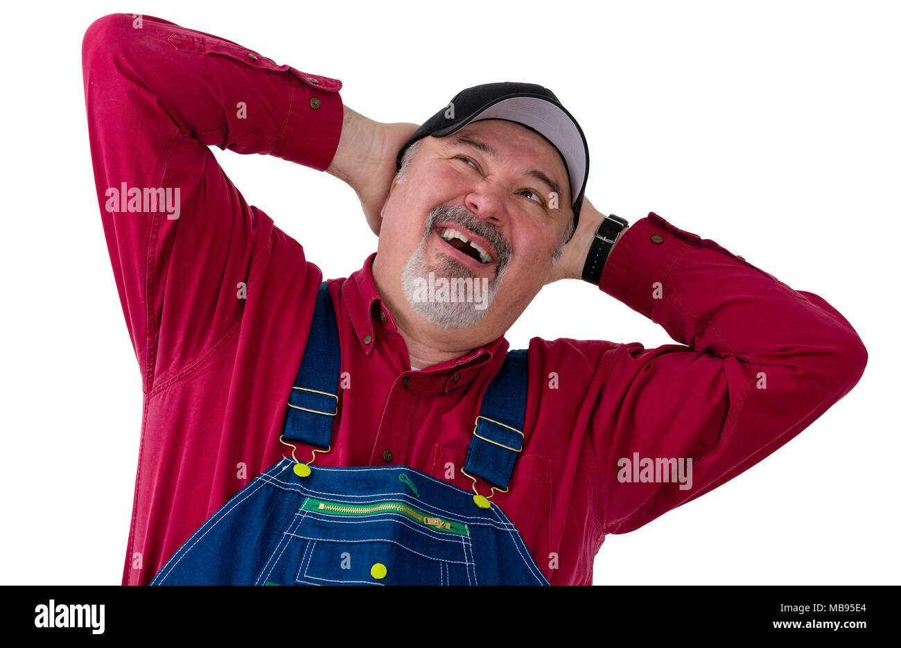 Worker, farmer or gardener in overalls with his hands behind his head looking up with his mouth open as though speaking and a thoughtful expression ov Stock Photo