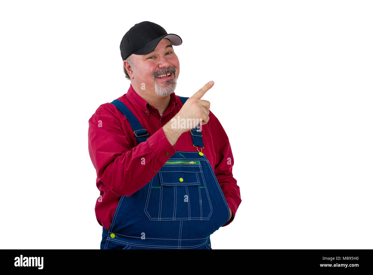 Middle-aged male worker pointing with his finger up at copy space, standing isolated on white background, wearing blue uniform overalls, red shirt and Stock Photo