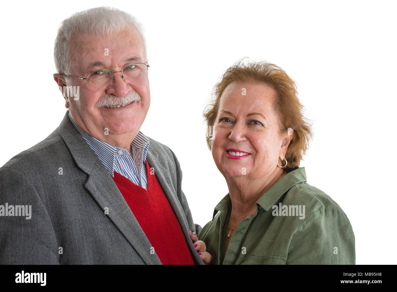 Happy friendly loving senior couple standing close together in an embrace smiling happily at the camera isolated on white Stock Photo