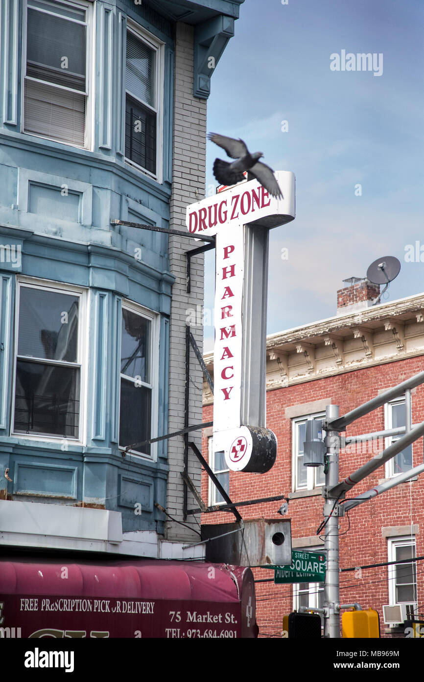 A pigeon flying over a drug store sign in Paterson, NJ Stock Photo