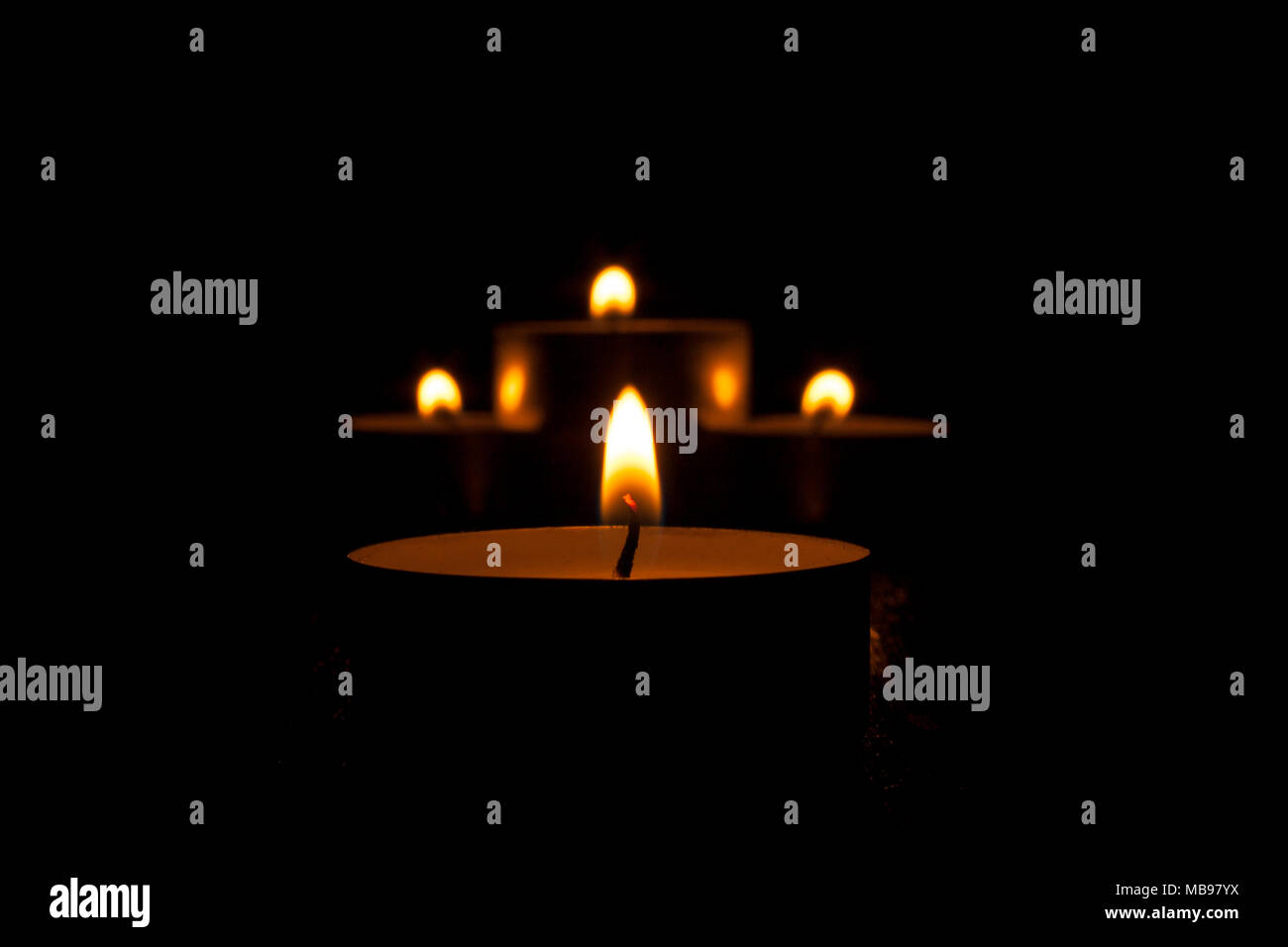 Candle tealights burning on a black background Stock Photo