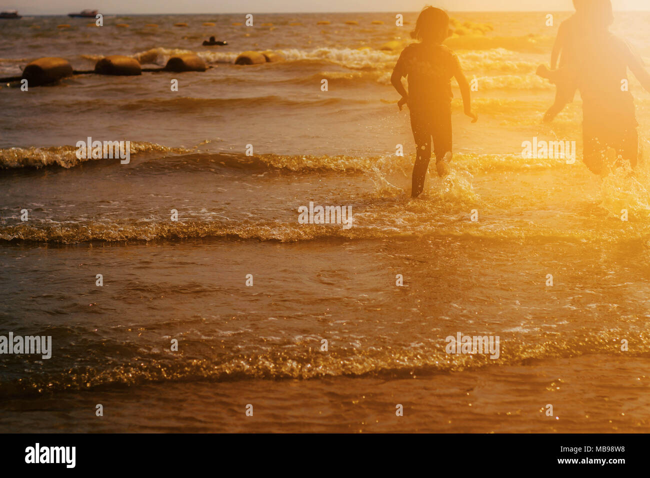 child is playing sea water with the sunset Stock Photo - Alamy
