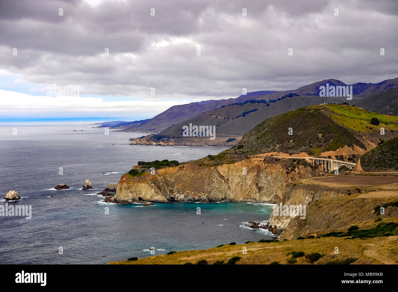 Aerial view of Bixby Creek Bridge, Cabrillo Highway 1, California, USA. Coastal landscape, Pacific ocean, rolling green hills and grey cloud skies Stock Photo