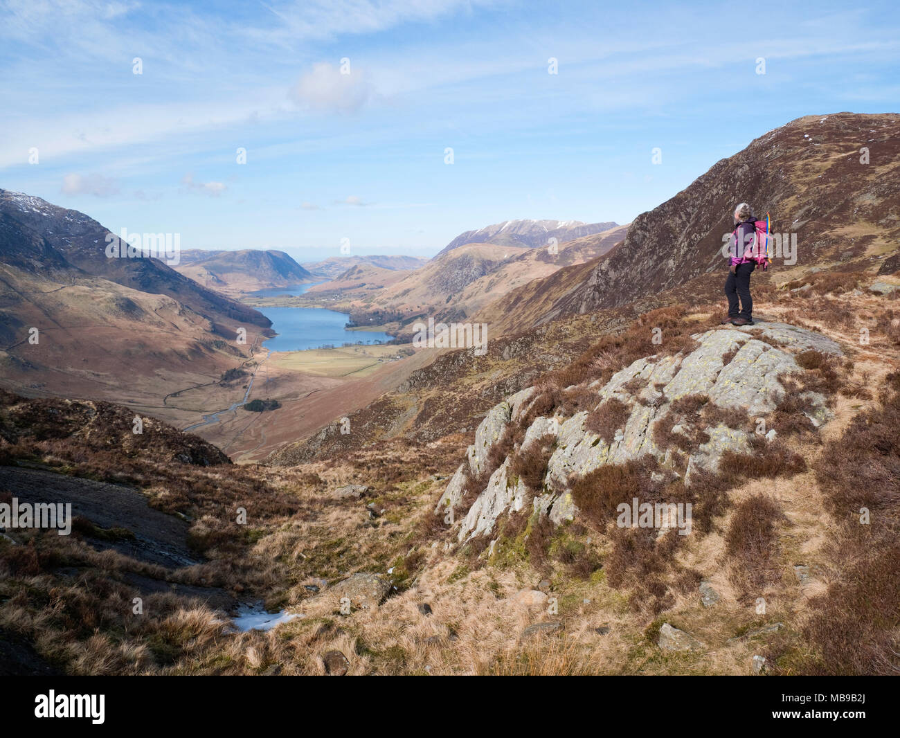 Female hiker admires view from Little Round How, Fleetwith Pike along Warnscale Bottom to Buttermere, with Mellbreak rising over Crummock Water beyond Stock Photo