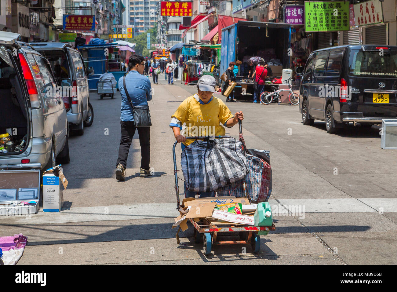 An Asian woman pushes a trolley laden with bags through Tai Nan Street,  Hong Kong. She is collecting cardboard and plastic waste for recycling  Stock Photo - Alamy