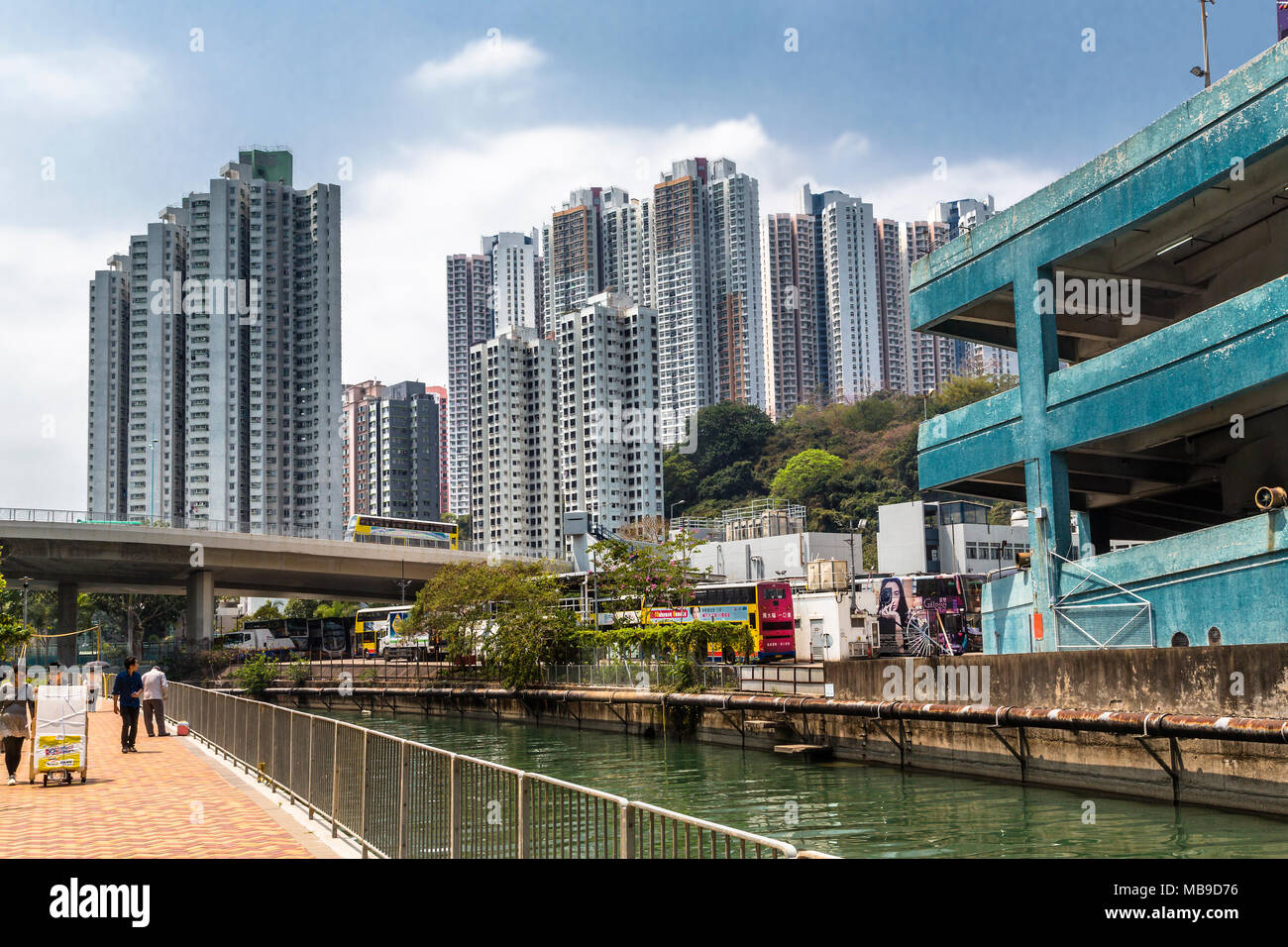 Towering high rise apartments loom over a section of the New World First Bus Services depot in Aberdeen, Hong Kong. Stock Photo