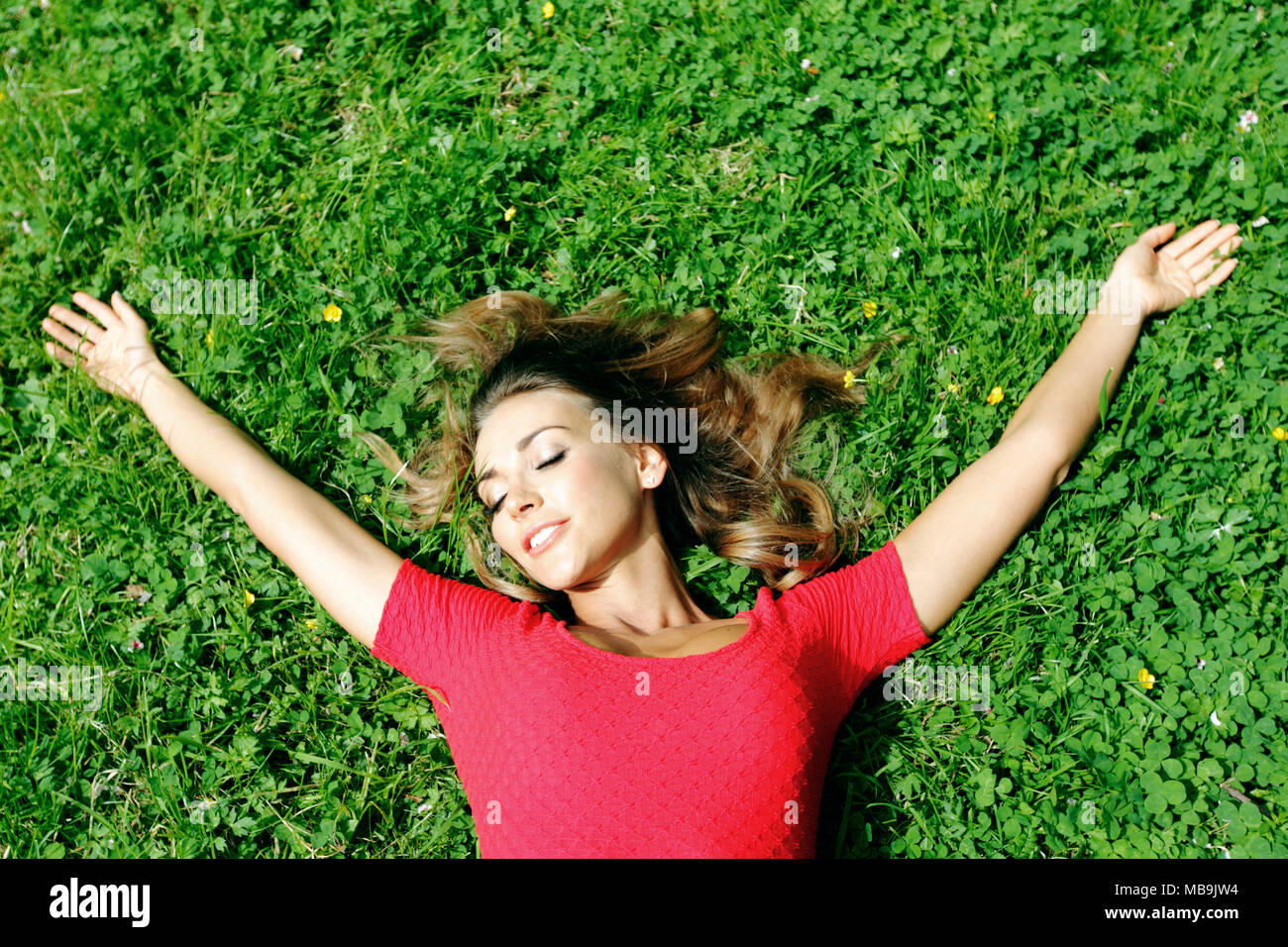 beautiful young woman in red dress lying on grass Stock Photo - Alamy