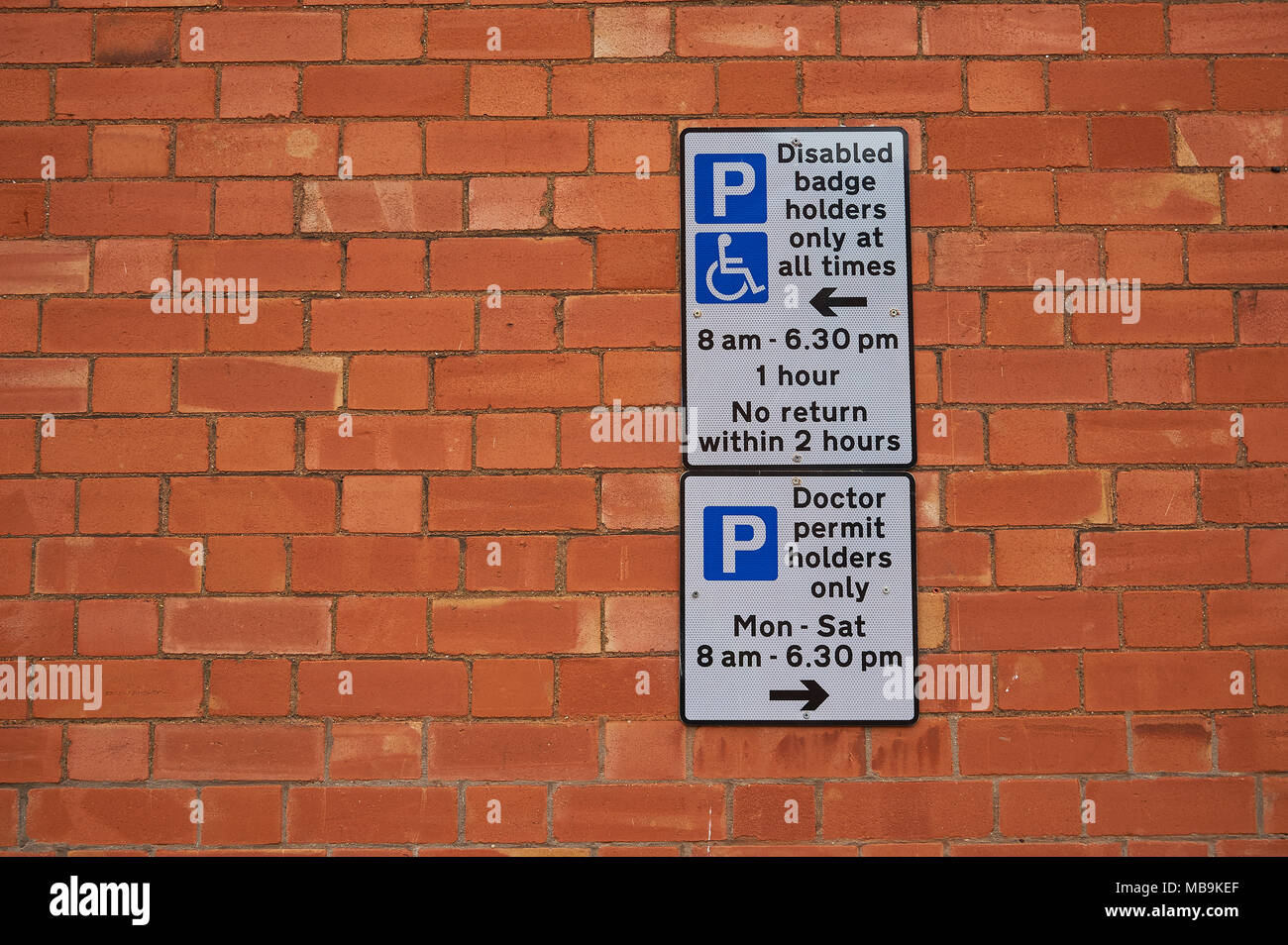 Rectangular sign with car parking instructions and time restrictions on a brick wall Stock Photo