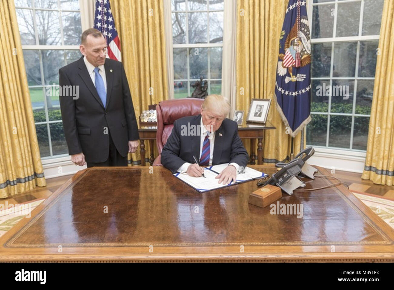 WASHINGTON, DC - WEEK OF April 03: President Donald J. Trump, joined by the Randolph D. ÒTexÓ Alles, Director of the U.S. Secret Service, signs H.R.3731-the U.S. Secret Service Retention Act of 2018, in the Oval Office at the White House, Tuesday, April 3, 2018, in Washington, D.C. The enrolled bill removes certain limits on overtime pay earned by employees of the U.S. Secret Service, who either provide protective services in calendar year of 2017 or will provide them in 2018.    People:  President Donald Trump Stock Photo