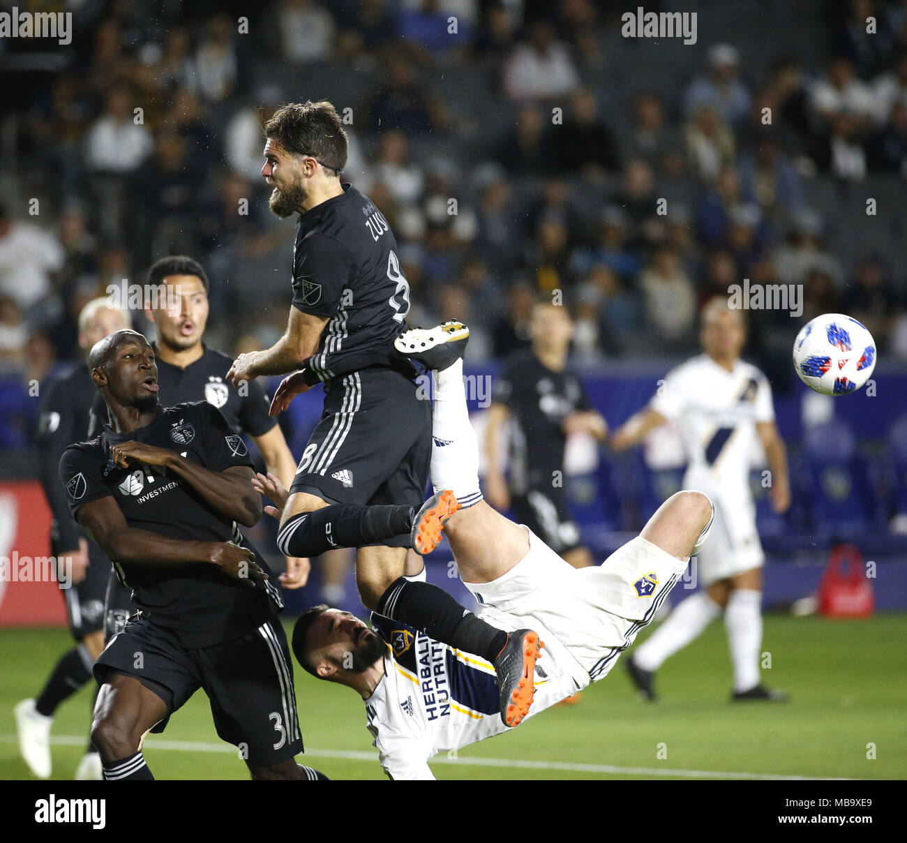 April 8, 2018 - Los Angeles, California, U.S - Los Angeles GalaxyÃ•s midfielder Romain Alessandrini (7) of France, goes up for a reverse kick against Sporting Kansas CityÃ•s defender Graham Zusi (8) and Sporting Kansas CityÃ•s defender Ike Opara (3) during the 2018 Major League Soccer (MLS) match between Los Angeles Galaxy and Sporting Kansas City in Carson, California, April 8, 2018. Sporting Kansas City won 2-0. (Credit Image: © Ringo Chiu via ZUMA Wire) Stock Photo