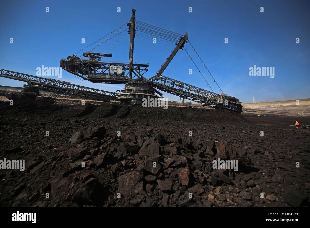 06 April 2018, Germany, Grevenbroich: An employee of RWE Power stands in front of a bucket wheel excavator that mines brown coal at the surface mining Garzweiler in the Rhenish lignite mining region. Photo: Oliver Berg/dpa Stock Photo
