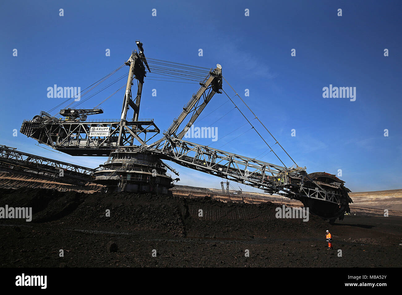 06 April 2018, Germany, Grevenbroich: An employee of RWE Power stands in front of a bucket wheel excavator that mines brown coal at the surface mining Garzweiler in the Rhenish lignite mining region. Photo: Oliver Berg/dpa Stock Photo