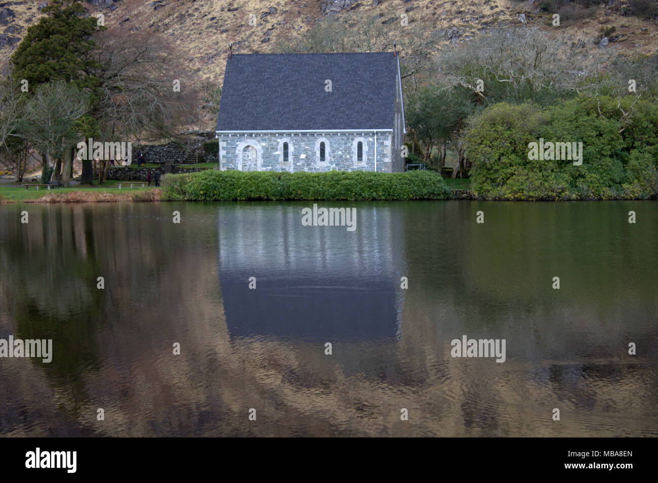 gougane barra church and  shrine of Saint Finbarr, the first bishop of cork, reflected in the atmospheric lake surrounding the church. Stock Photo