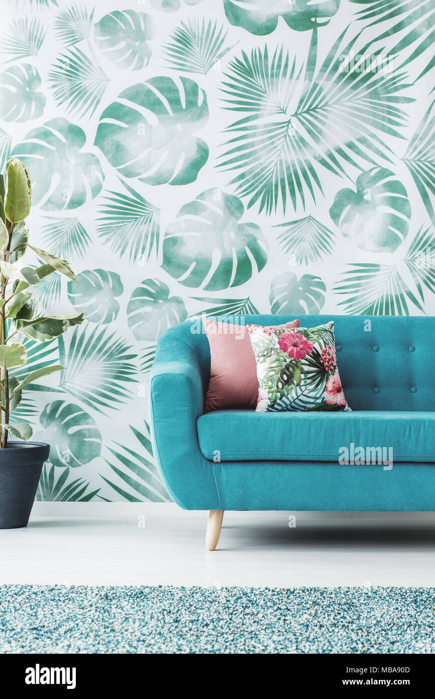 Cushions on turquoise sofa against green wallpaper in living room