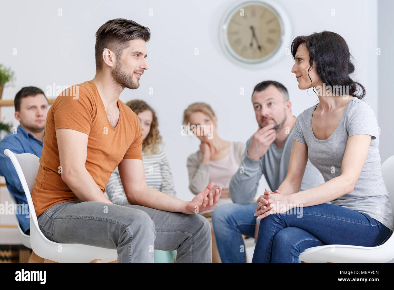 Young man expressing love and appreciation to his mother in psychotherapy with family in the background Stock Photo