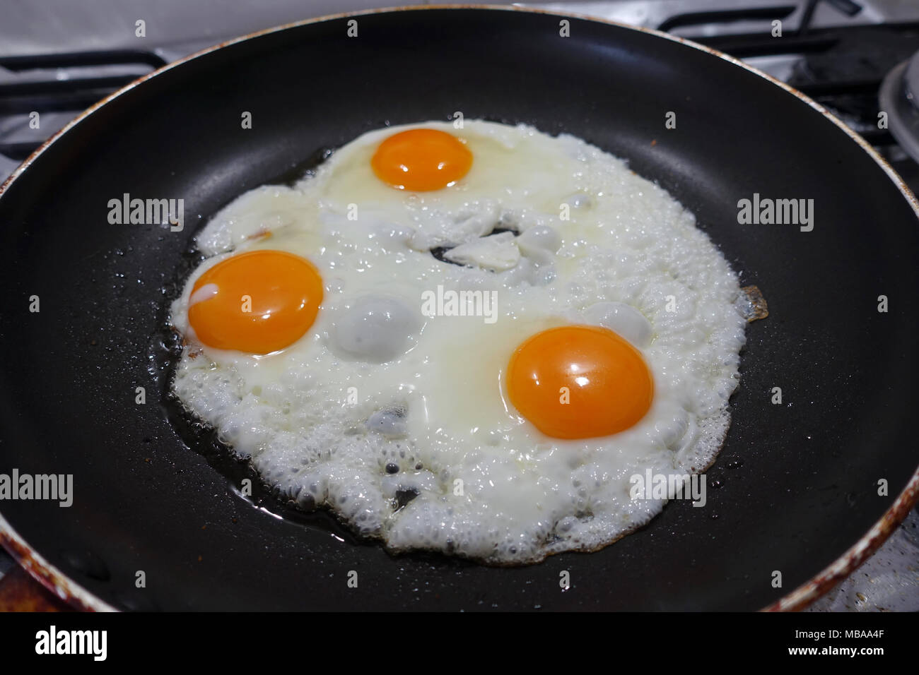 Frying three eggs in non stick pan Stock Photo