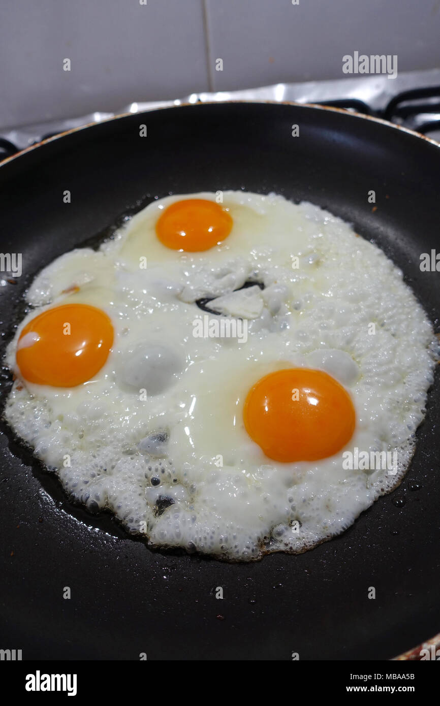 Frying three eggs in non stick pan Stock Photo