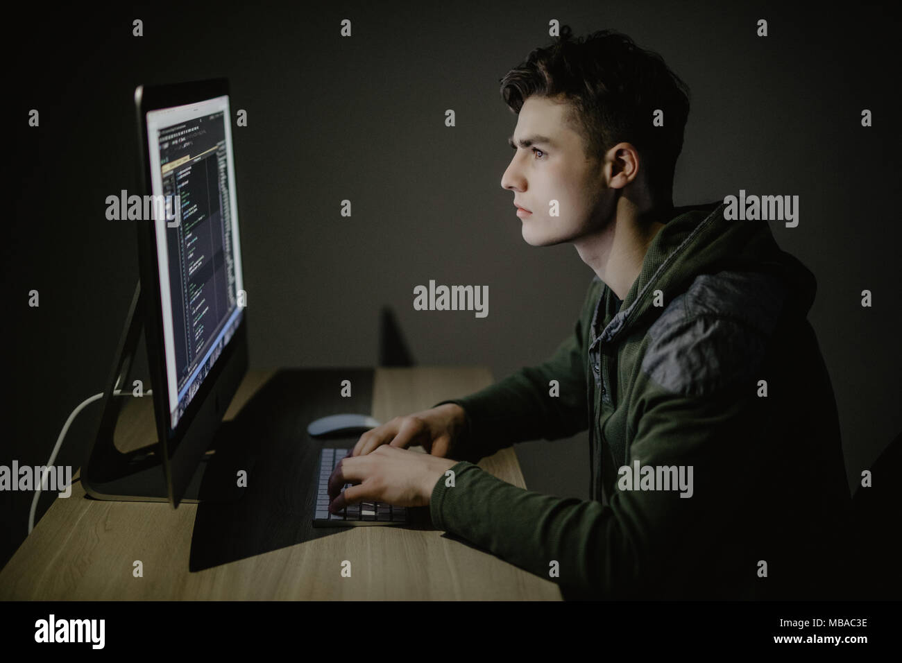 Handsome male programmer, IT person, hacker, works in computer on internet, black background. Stock Photo