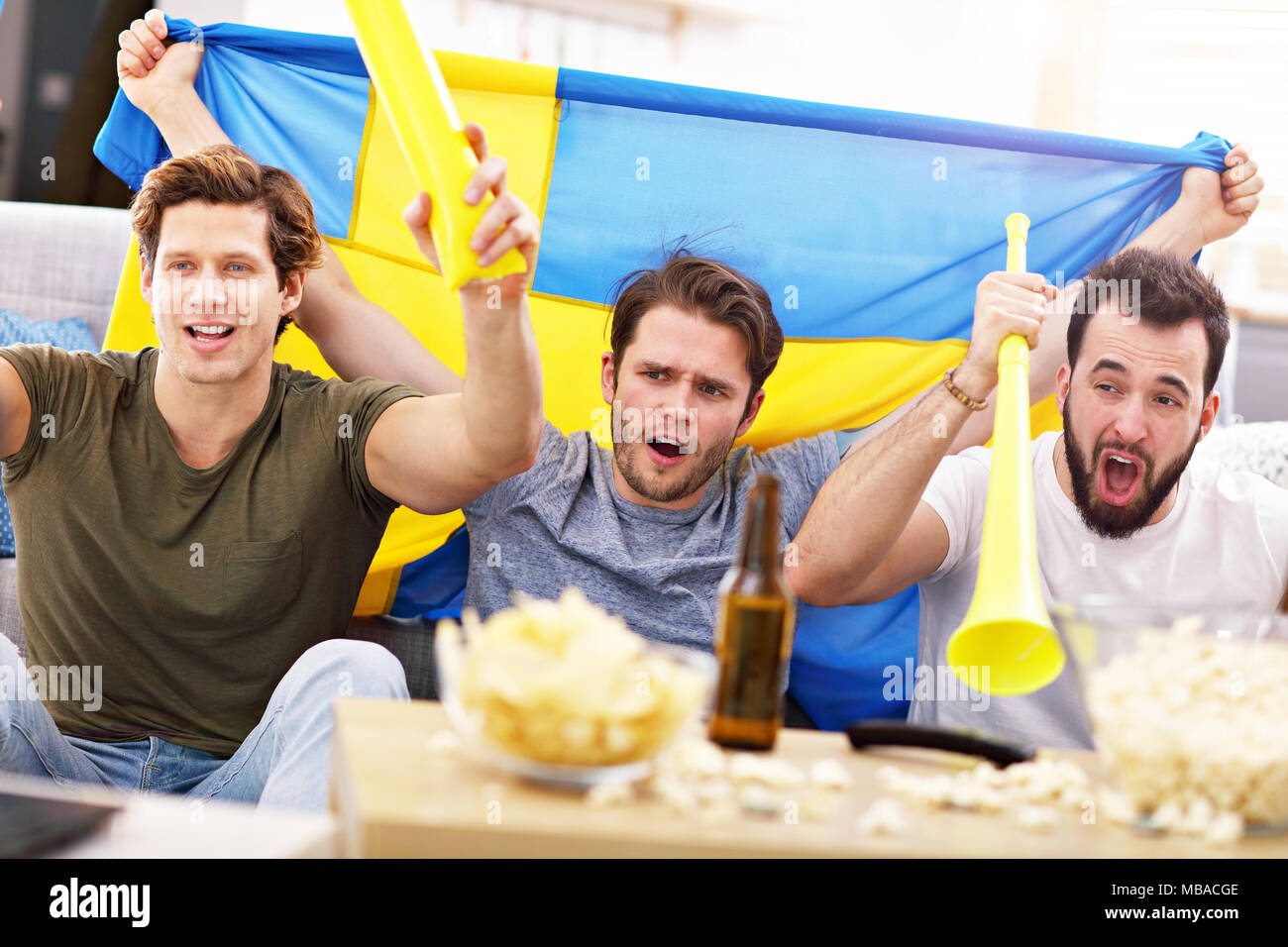 Happy male friends cheering and watching sports on tv Stock Photo