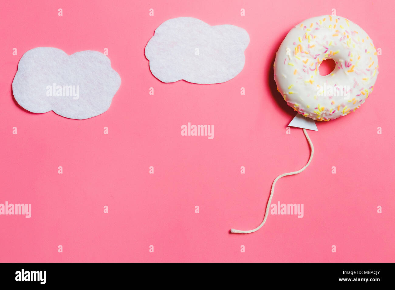 Donut on Pink, Creative Food Minimalism, Donut in Shape of Balloon in Sky with Clouds, Top View with Copy Space, Toned Stock Photo