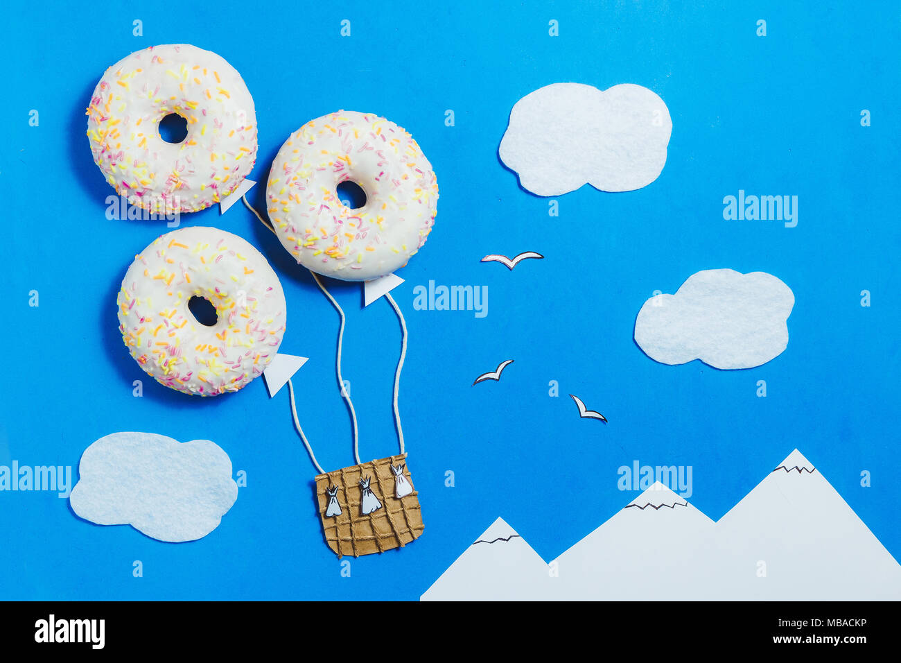 Creative Food Minimalism, Donut in Shape of Aerostat in Blue Sky with Clouds, Mountains, Top View, Copy Space, Travel Stock Photo