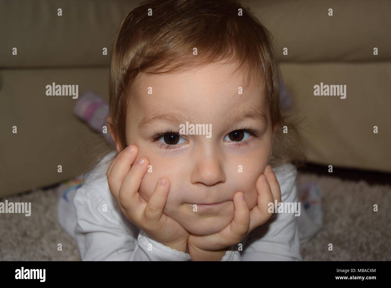 the little girl is lying on the carpet Stock Photo - Alamy