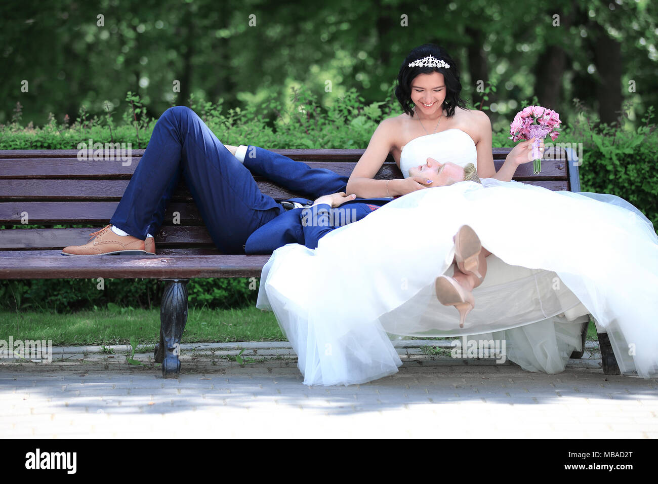 bride embraces the groom,sitting on a bench in the Park Stock Photo - Alamy