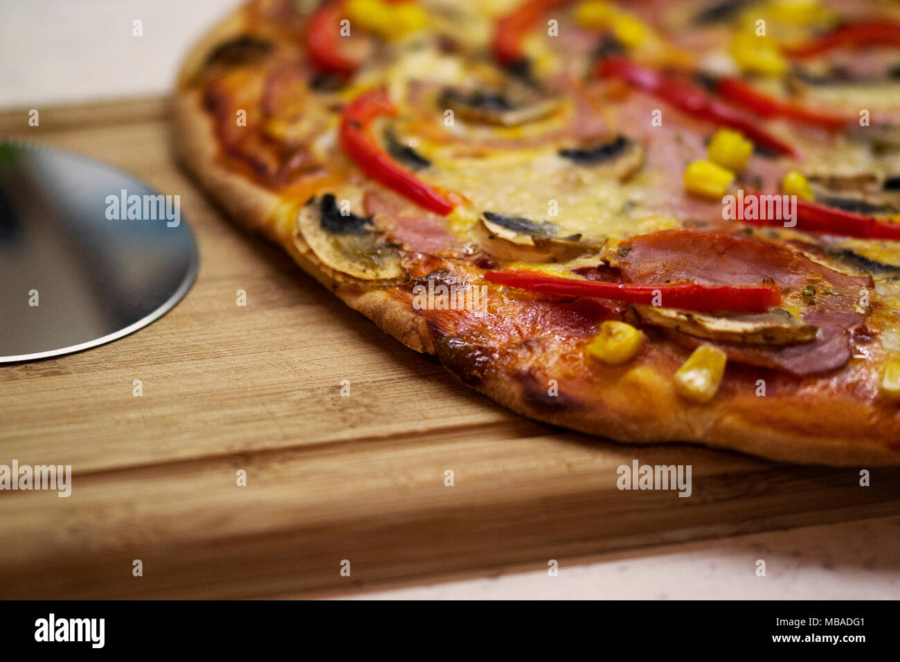 Close-up of a homemade pizza on the kitchen counter, near a pizza slicer Stock Photo
