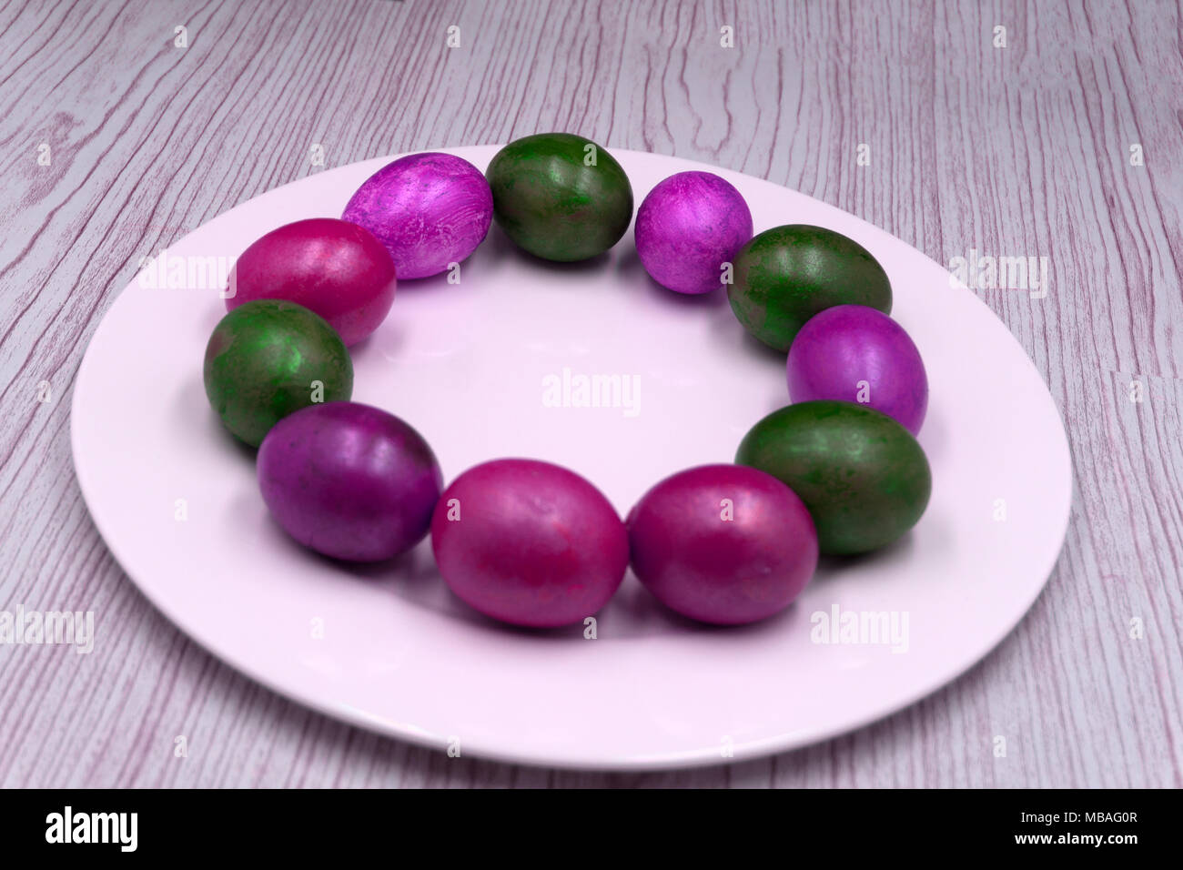 Painted eggs in wooden plate against rustic background Stock Photo