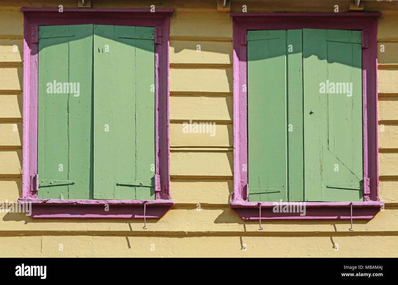 building detail with yellow walls, green shutters, and pink trim windows Stock Photo Alamy