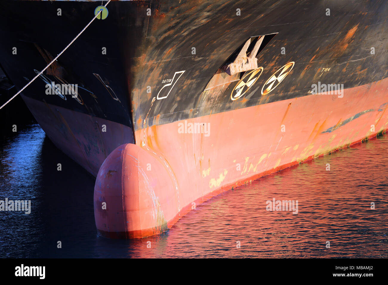 bulbous bow detail of cargo ship showing mooring line, water line