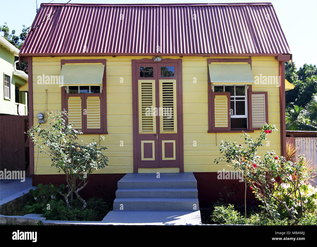 typical rural Caribbean style home with yellow wall and dark red trim typical rural Caribbean style home with yellow wall and dark red trim