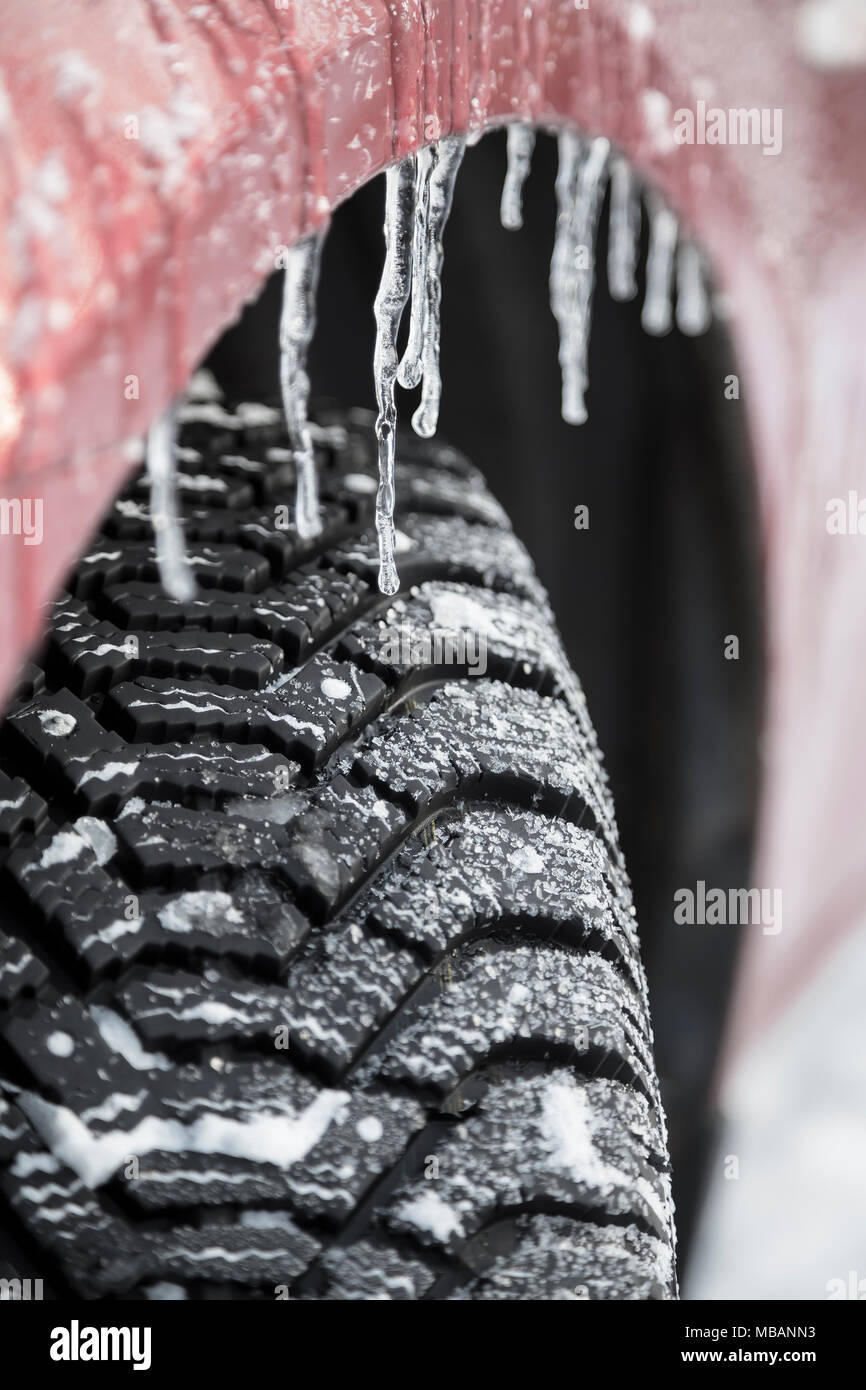 Tread winter tires with studs and icicles on the wheel of a car Stock Photo