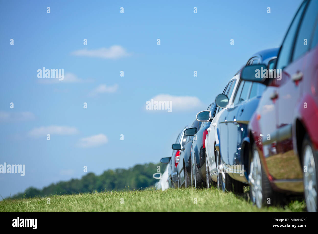 Cars parking in line in the green at what might be a festival Stock Photo