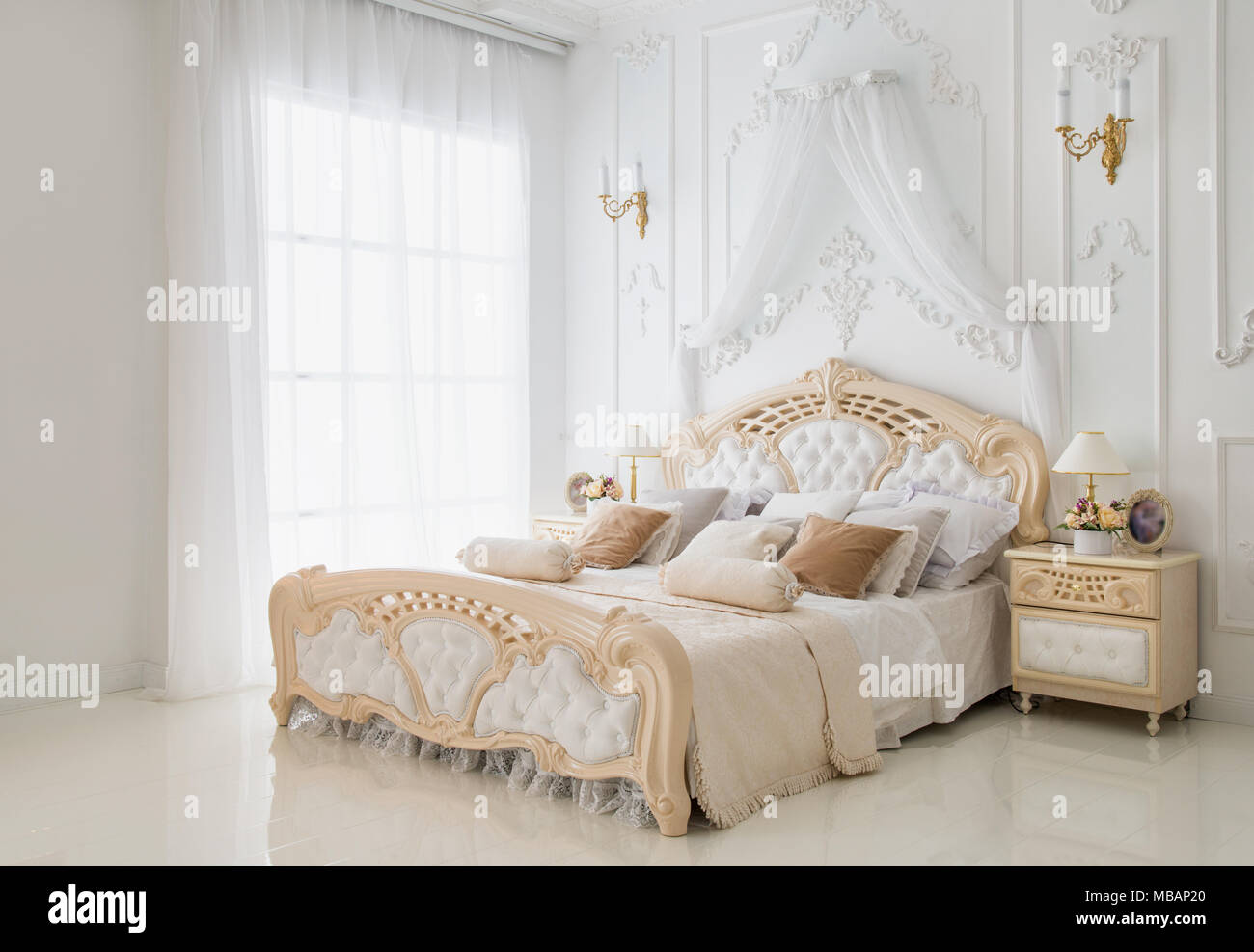 Cozy classic white bedroom, walls decorated with fretwork Stock Photo