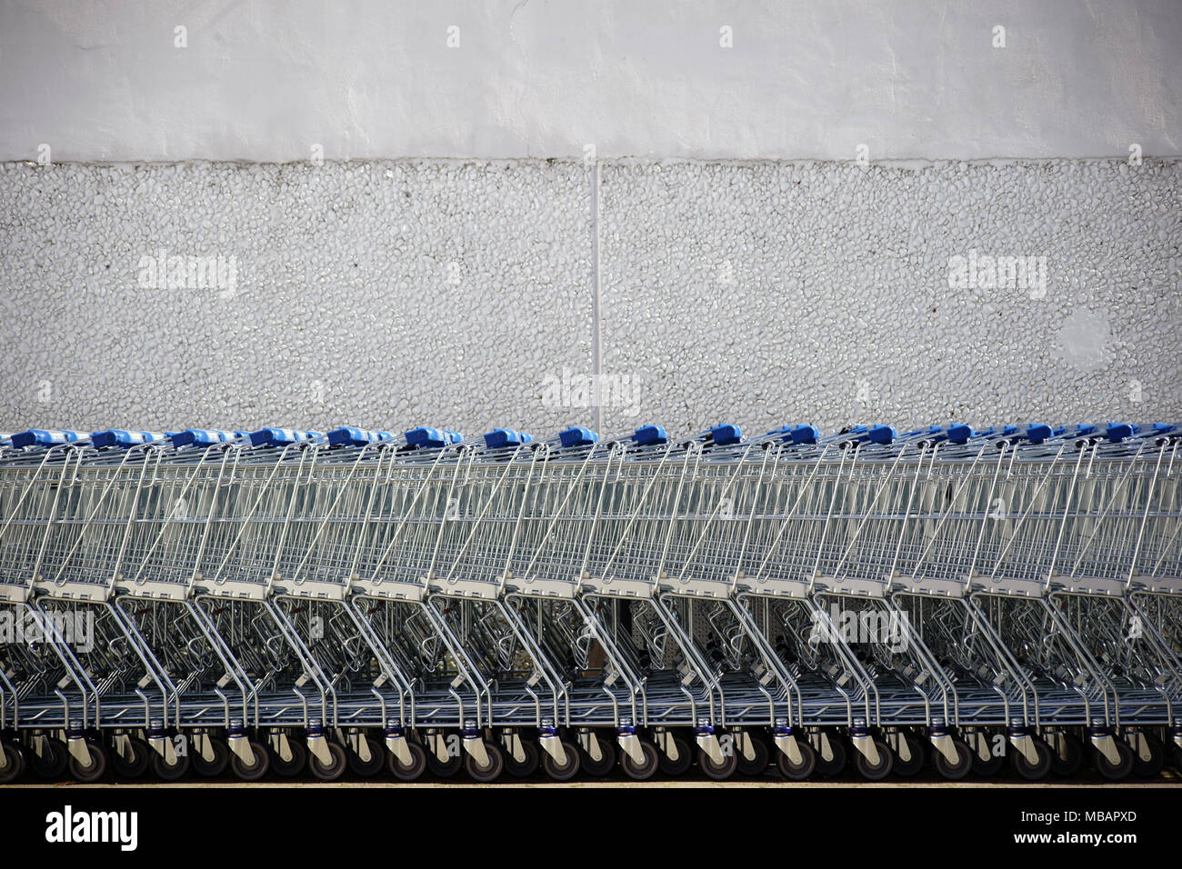 Shopping carts put together in a row in front of the bright wall of a