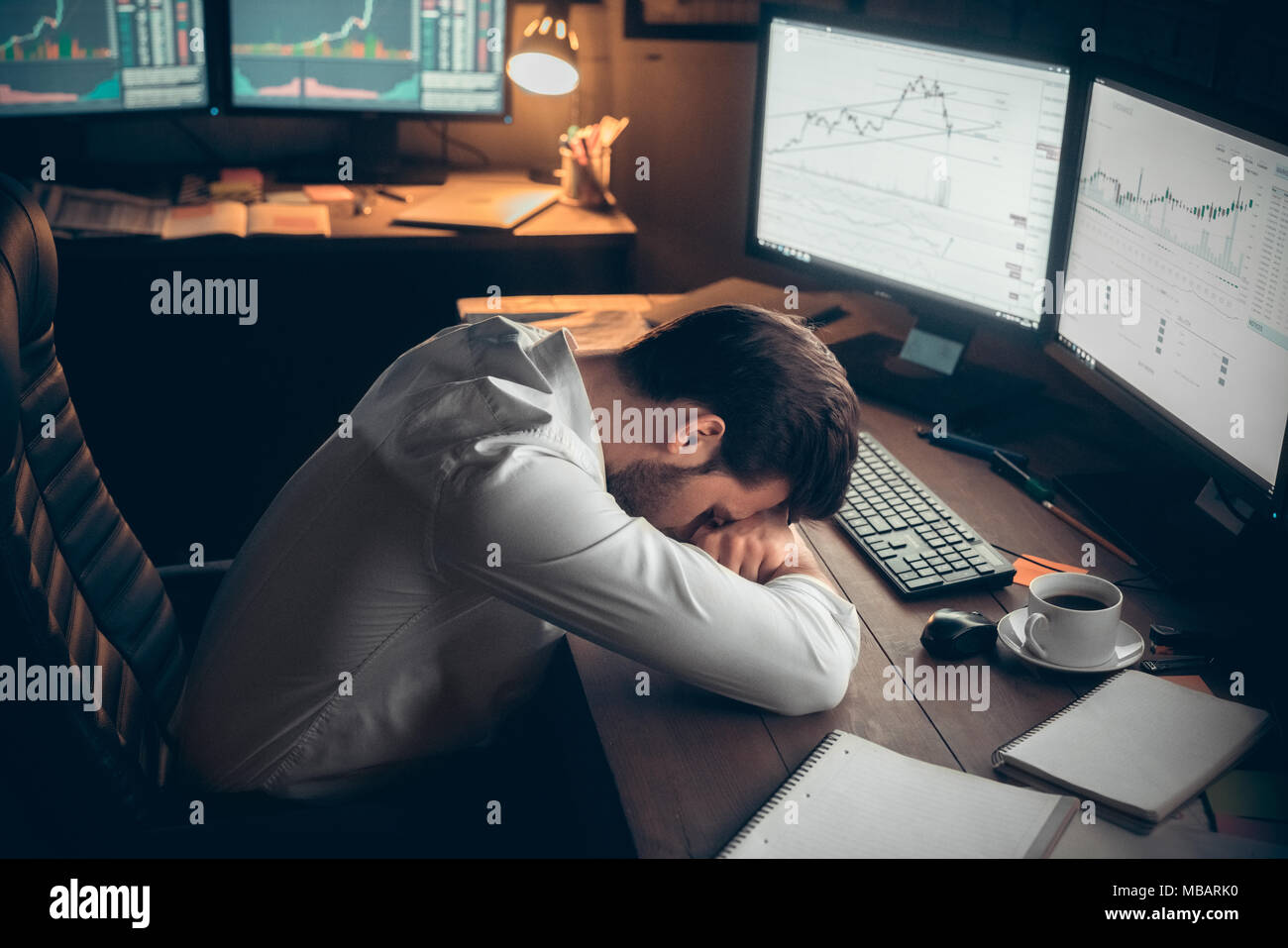 Young bearded man trader at office lying on table tired Stock Photo
