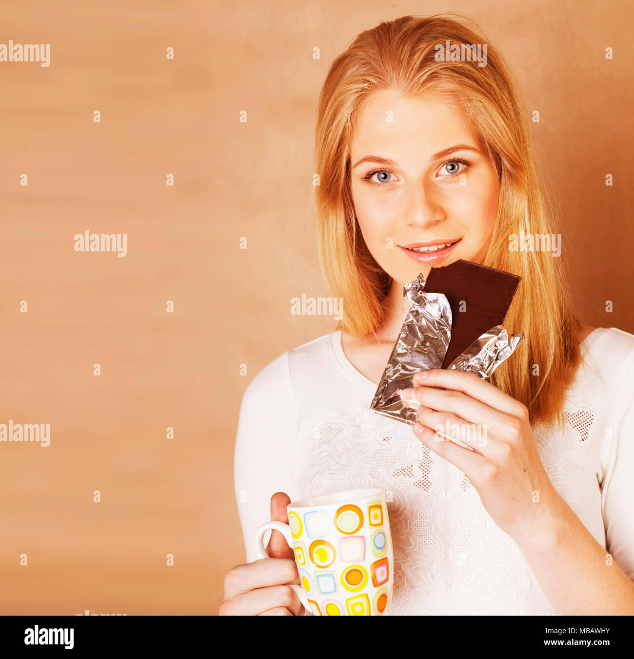 young cute blond girl eating chocolate and drinking coffee close Stock