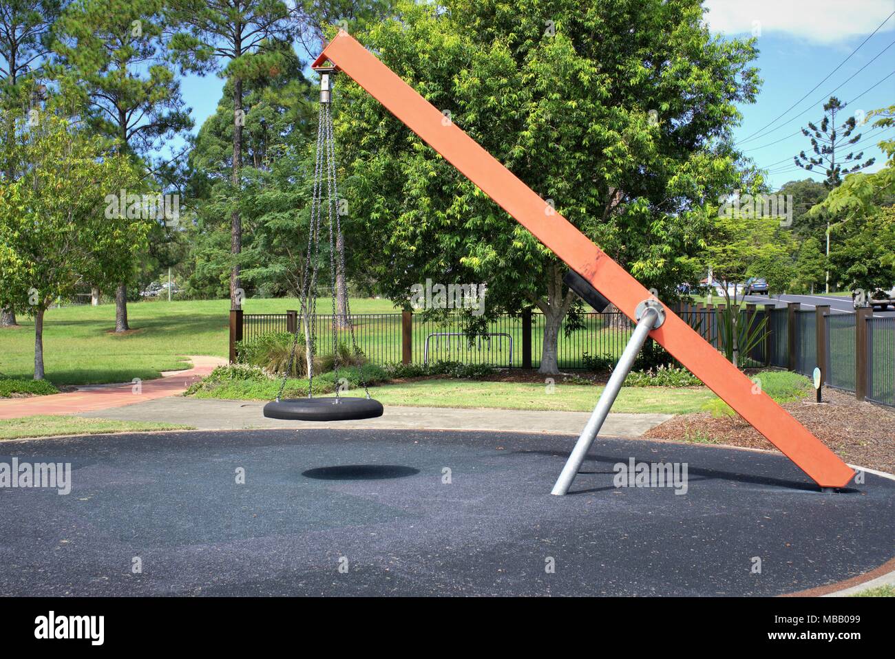 Swing in public park. Empty tire swing tied with metal chains to metal beam in children's park. Kids park in Australia. Stock Photo