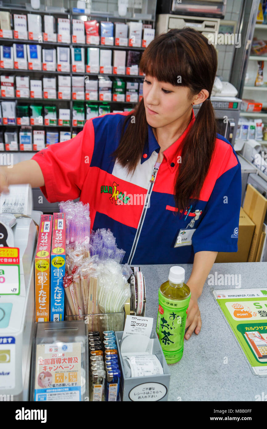Tokyo Japan,Ikebukuro,Circle K Sunkus Convenience Store,Asian woman female women adult adults,uniform,cashier,check out,bottle,green tea,Japanese,Japa Stock Photo